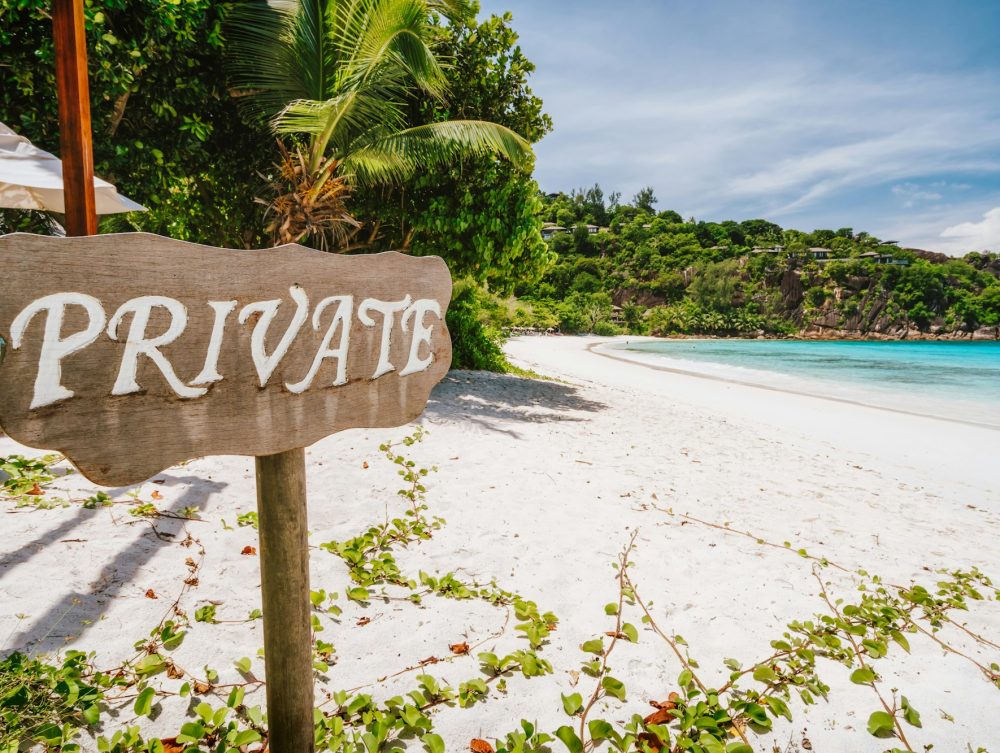 private-sign-at-tropical-sandy-beach-with-blue-ocean-lagoon-in-background-at-mahe-island-seychelles